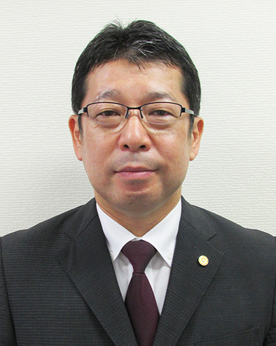 画像：メガネをかけスーツを着た福岡県行政書士会会長、田村公隆